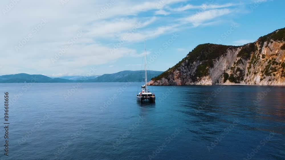 Sailing yachts anchored in a blue calm sea with majestic mountains in the background Sailing yachts anchored in a blue calm sea with majestic mountains in the background