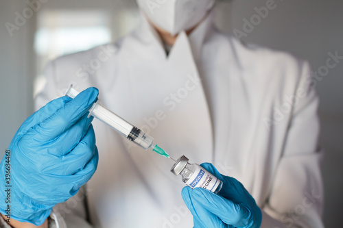 Doctor holding syringe and laboratory injection vial with Coronavirus or Covid-19 vaccine