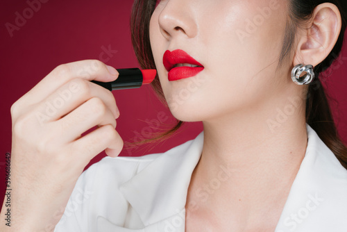 Close up portrait of beautiful young asian woman applying red lipstick.