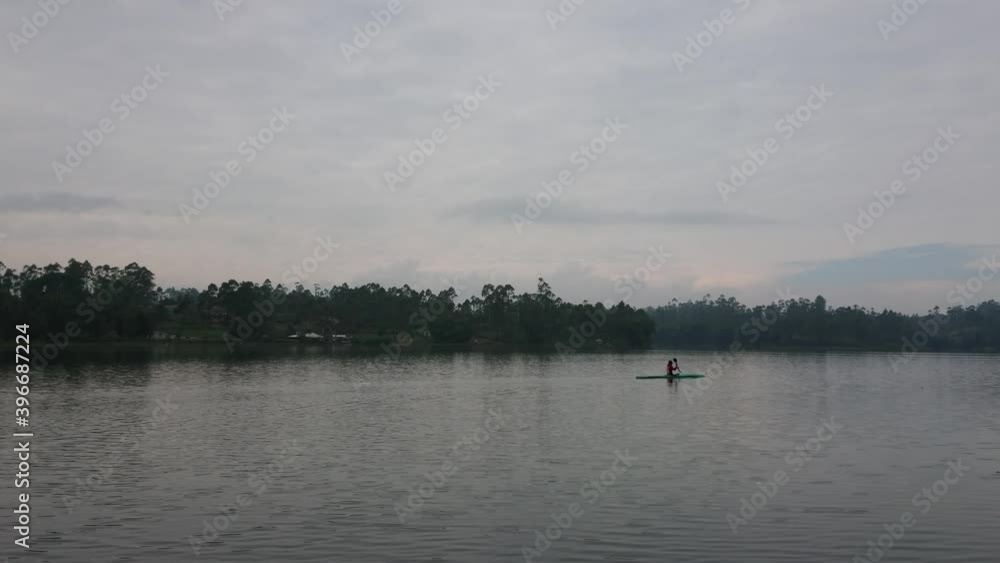 Canoeists enjoy paddling on a lake surrounded by forests and mountains. A man canoeing on a large lake at dawn Canoeists enjoy paddling on a lake surrounded by forests and mountains. A man canoeing on a large lake at dawn