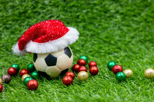 Soccer ball with Santa hat on green grass