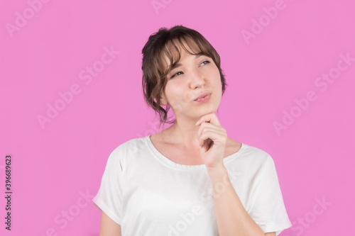 Girl on isolated pink background thinks about an idea.