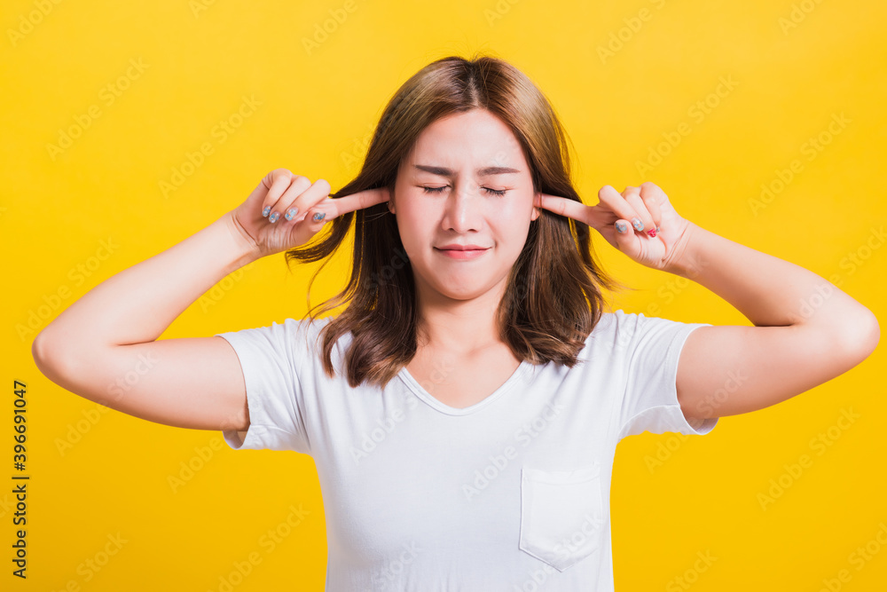 Asian Thai happy portrait beautiful cute young woman smile have closed palms ears with palms and close eyes, studio shot isolated on yellow background with copy space Asian Thai happy portrait beautiful cute young woman smile have closed palms ears with palms and close eyes, studio shot isolated on yellow background with copy space