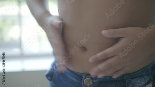 Overweight boy touching fat on his belly, closeup