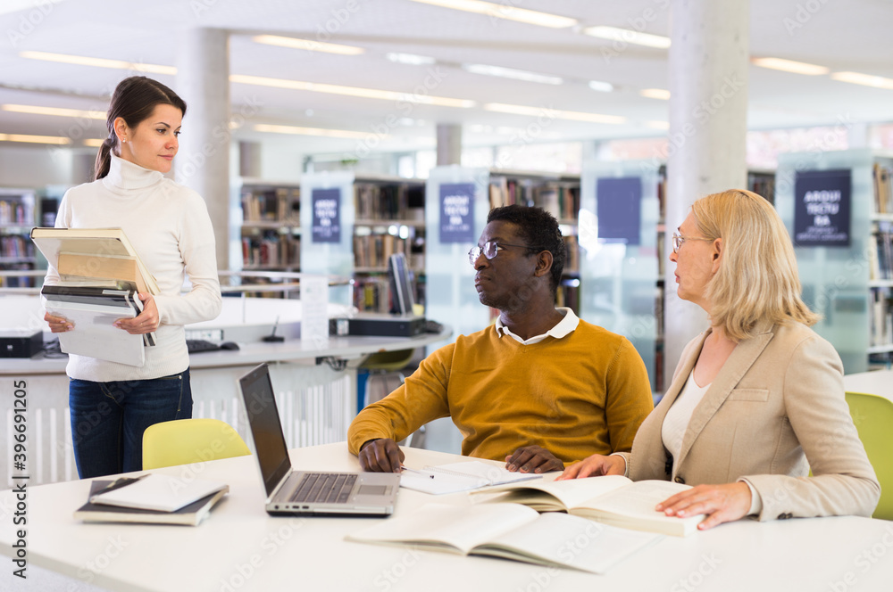 Fototapeta premium Teacher and adult students talking in the library. High quality photo