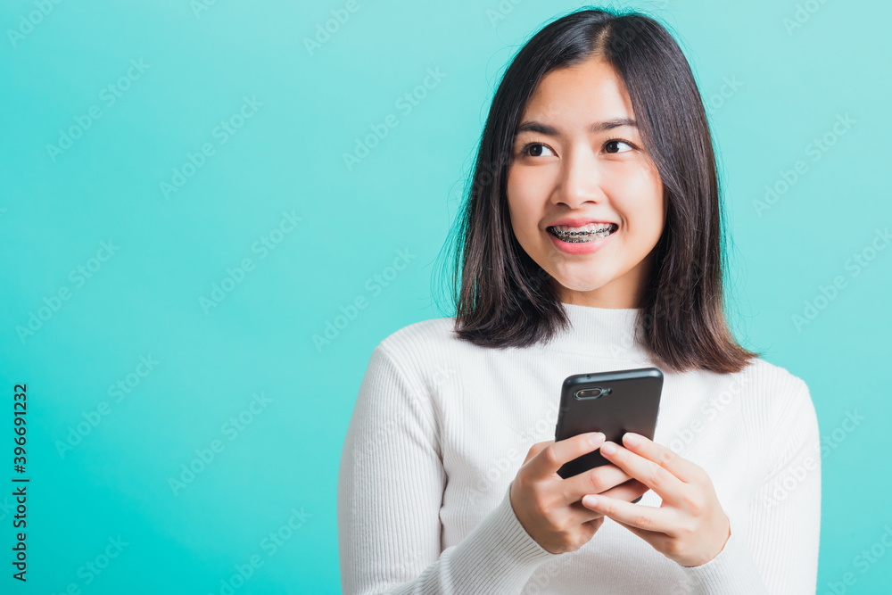 Portrait of Asian woman smile she holding and typing text message on a smartphone, female excited cheerful her reading mobile phone some social media isolated on a blue background, Technology concept Portrait of Asian woman smile she holding and typing text message on a smartphone, female excited cheerful her reading mobile phone some social media isolated on a blue background, Technology concept