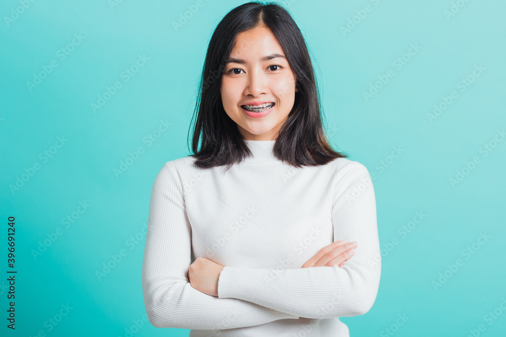 Young beautiful Asian woman smiling with crossed arms, Portrait of positive confident female stand cross one's arm, studio shot isolated on a blue background Young beautiful Asian woman smiling with crossed arms, Portrait of positive confident female stand cross one's arm, studio shot isolated on a blue background
