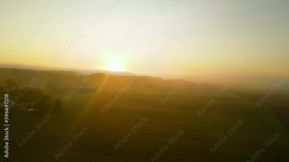 Beautiful aerial sideways drone shot of hazy golden sunrise over rural countryside fields Beautiful aerial sideways drone shot of hazy golden sunrise over rural countryside fields