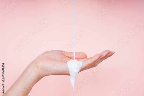 Woman hand with liquid lotion cream pouring from top screen.