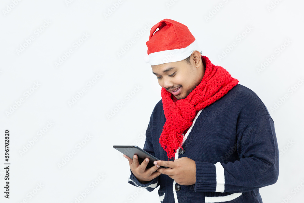 Asian man wearing a Santa hat look at tablet on white background Asian man wearing a Santa hat look at tablet on white background