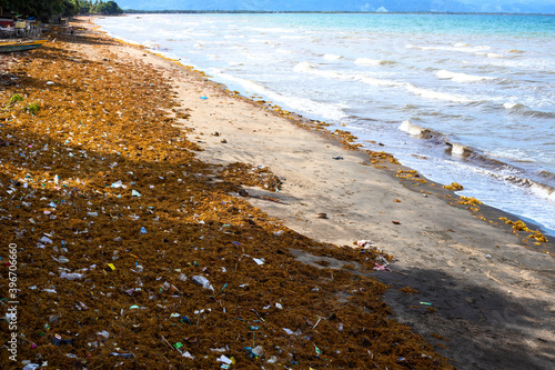 Sea water with waves, seaweed and garbage. Aquatic trash on tropical beach. Plastic pollution in ocean. Environmental problem of human impact on nature. Philippine island garbage