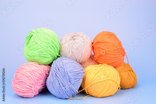 Piled multicolored wool for crocheting isolated on light blue background.