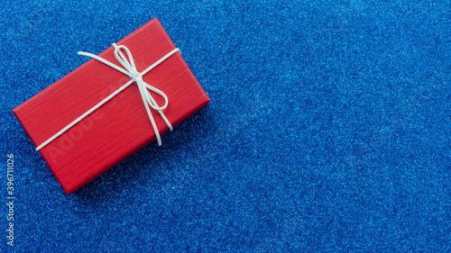 New Year's gift on a blue glitter background top view. Christmas background