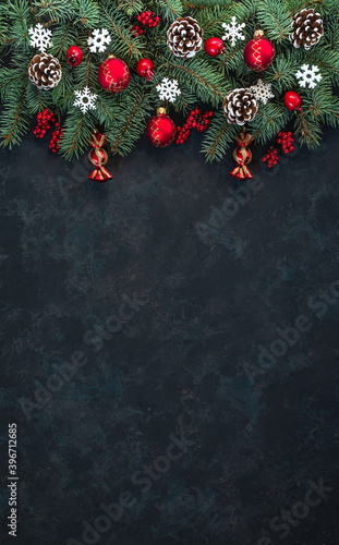 Christmas dark grunge horizontal background  top view. Fir twigs  red golden berries  baubles. Winter holidays  New Year decoration  pine tree branches  snow covered cones  flat lay  copy space.
