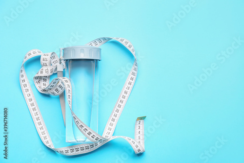 Bottle of water and measuring tape on color background