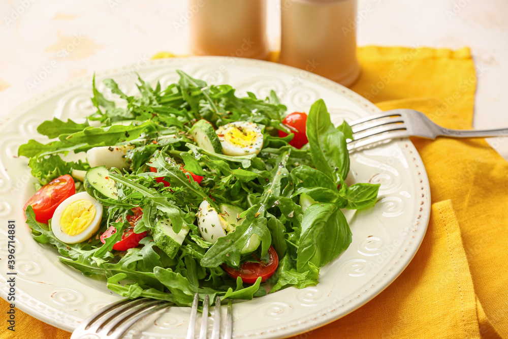 Plate with tasty arugula salad on light table Plate with tasty arugula salad on light table