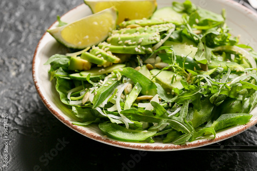 Plate with tasty arugula salad on dark background