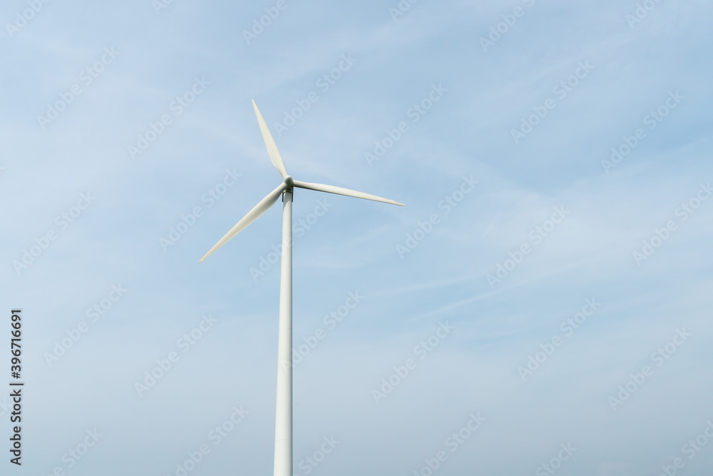 view of a modern windmill against a blue sky. The white blades of the wind turbine close up. Renewable energy source. Production of cheap and safe electricity. view of a modern windmill against a blue sky. The white blades of the wind turbine close up. Renewable energy source. Production of cheap and safe electricity.