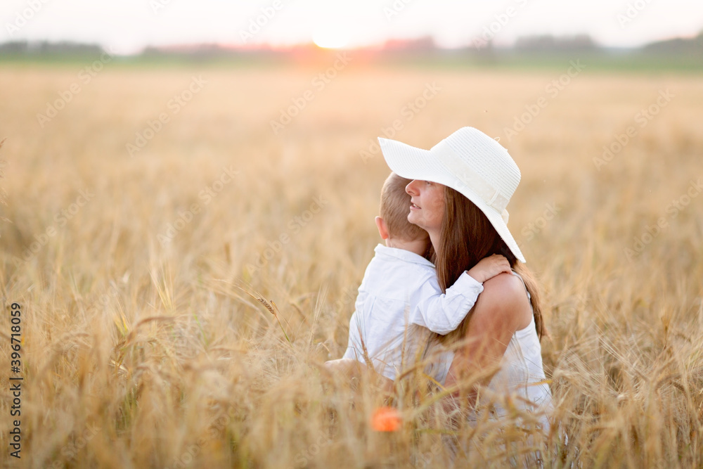 Caucasian beautiful mother hugs her child son in the summer wheat field at sunset, summer and harvest, rest in the village Caucasian beautiful mother hugs her child son in the summer wheat field at sunset, summer and harvest, rest in the village