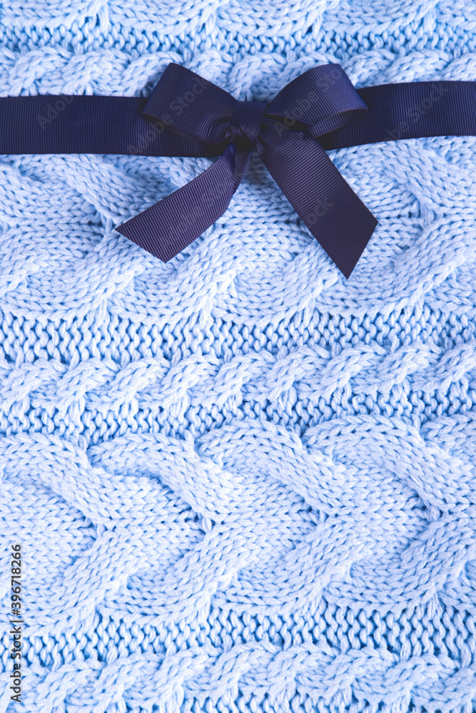 Beautiful wool knitted background in the pale blue color made like a present with the dark blue ribbon. Beautiful wool knitted background in the pale blue color made like a present with the dark blue ribbon.