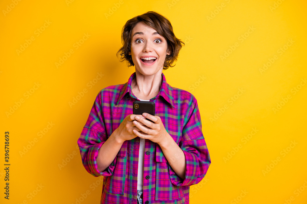 Photo of brown haired pretty woman amazed notification smartphone unbelievable isolated on yellow color background Photo of brown haired pretty woman amazed notification smartphone unbelievable isolated on yellow color background