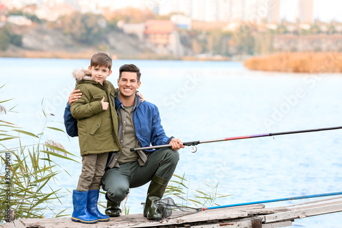 Little boy and his father fishing on river