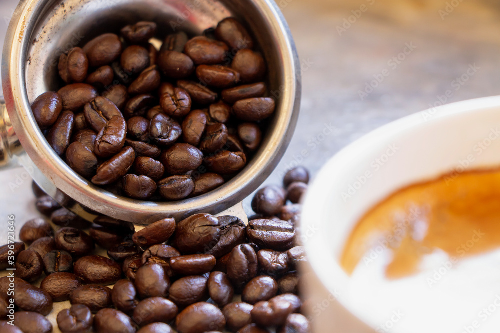 Fototapeta premium Close up of filter holder basket with organic dark brown roasted arabica coffee beans inside.