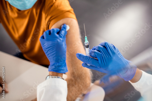 Close-up of doctor vaccinating senior patient at medical clinic.