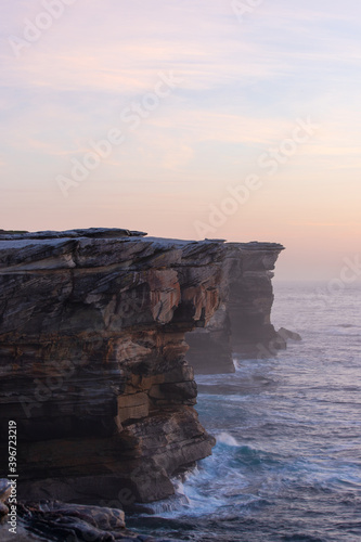Sunrise view of rock cliff layers along Sydney coastline, Australia.