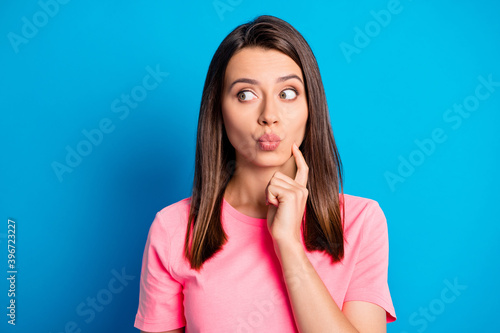 Photo portrait of curious pretty girl looking at empty space with pouted lips isolated on vivid blue color background