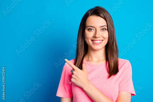 Photo portrait of pretty female student pointing at empty space smiling isolated on vibrant blue color background