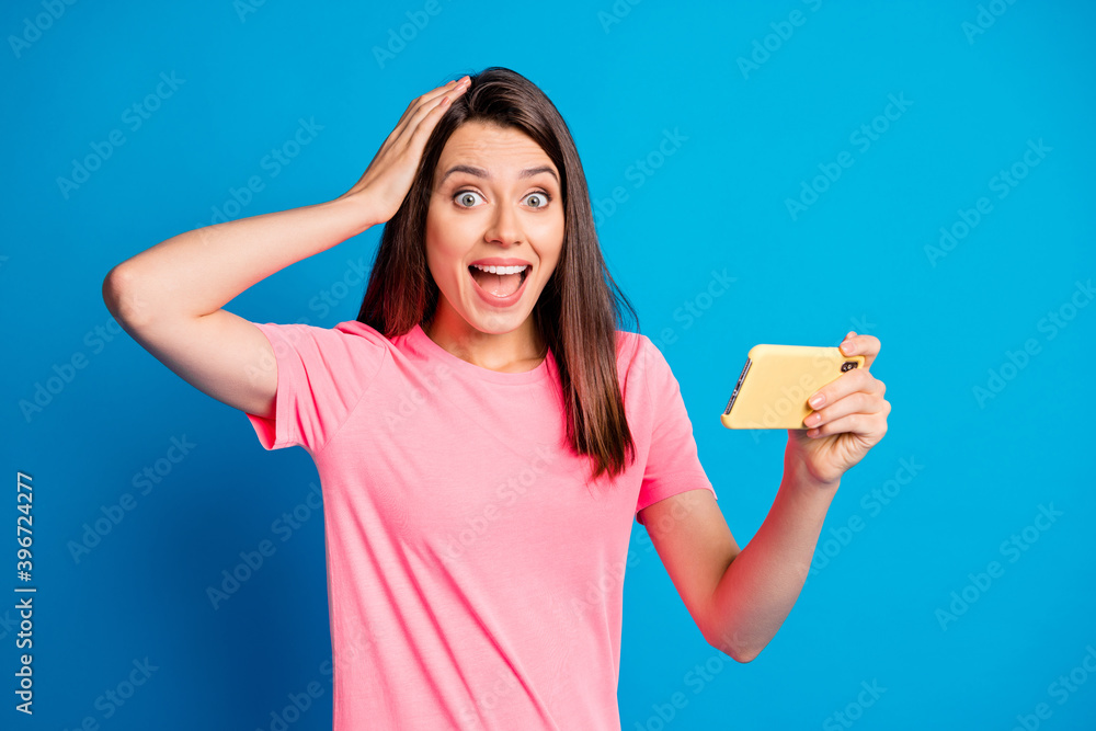Photo portrait of beautiful girl playing video game touching head with hand surprised isolated on bright blue color background