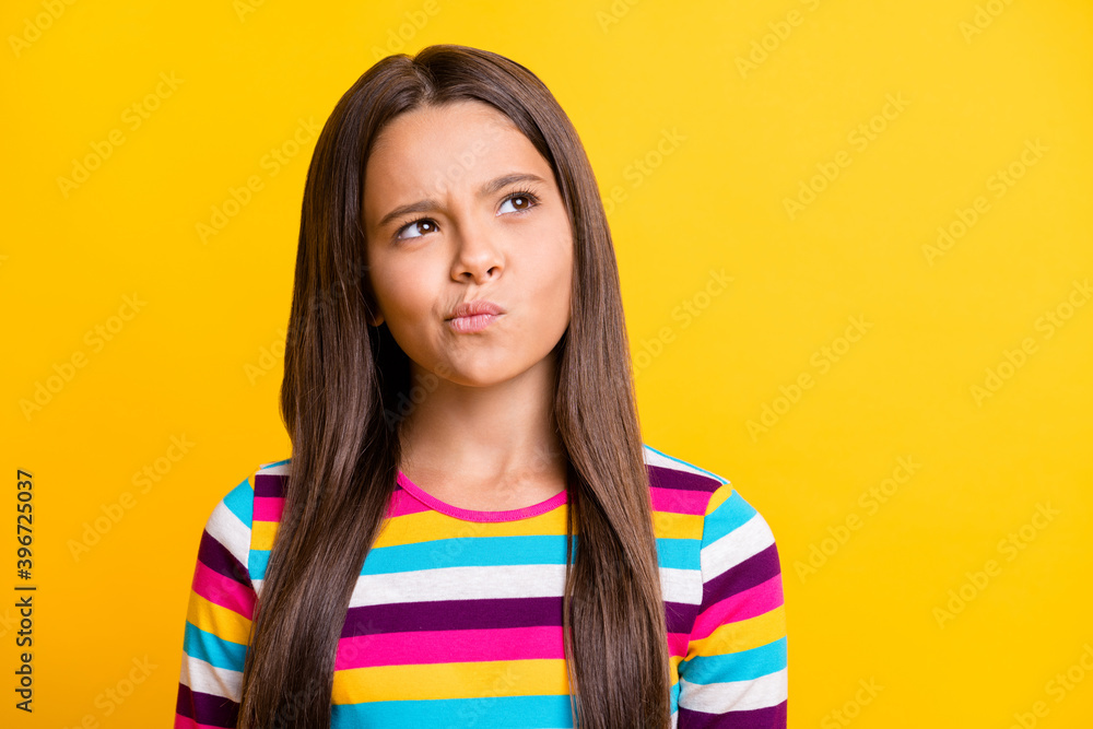 Photo of minded concentrated little girl look up empty space wear striped shirt isolated yellow color background Photo of minded concentrated little girl look up empty space wear striped shirt isolated yellow color background