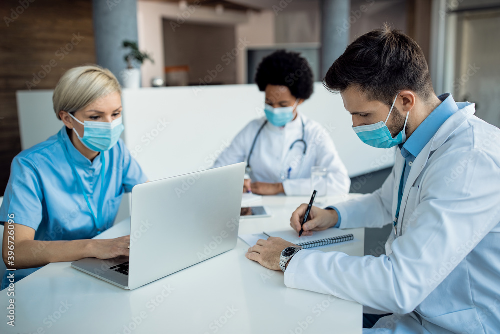 Male doctor taking notes while working with colleagues at medical clinic. Male doctor taking notes while working with colleagues at medical clinic.