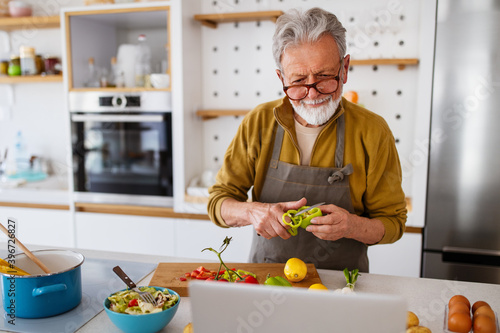 Valokuva Mature handsome man cooking in home kitchen
