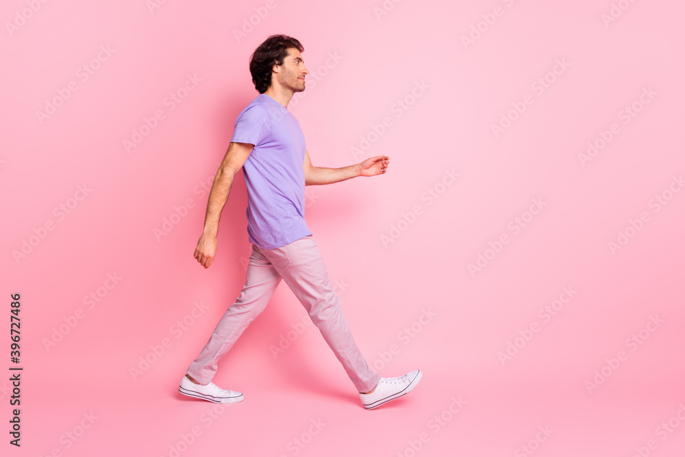 Full body profile photo of handsome person walking empty space purple outfit isolated on pink color background