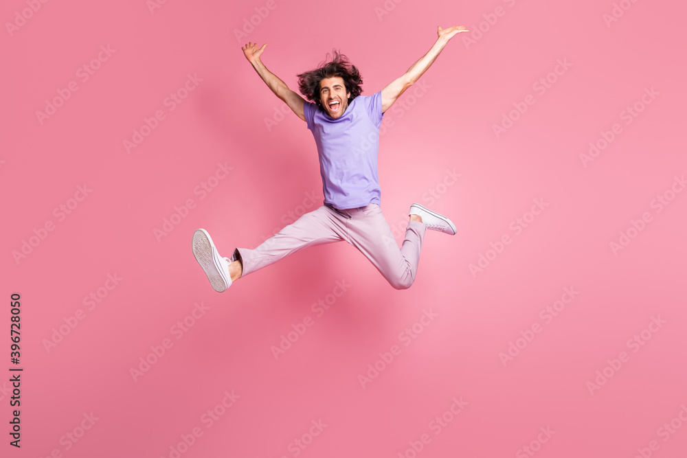 Full size photo of energetic young man raise hands jump in air success wear pink pants isolated on pink color background