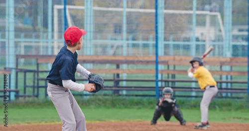 Baseball tournament at school, boys play baseball, the pitcher throws the ball toward a batter, batter successfully hits a fastball, 4k slow motion.