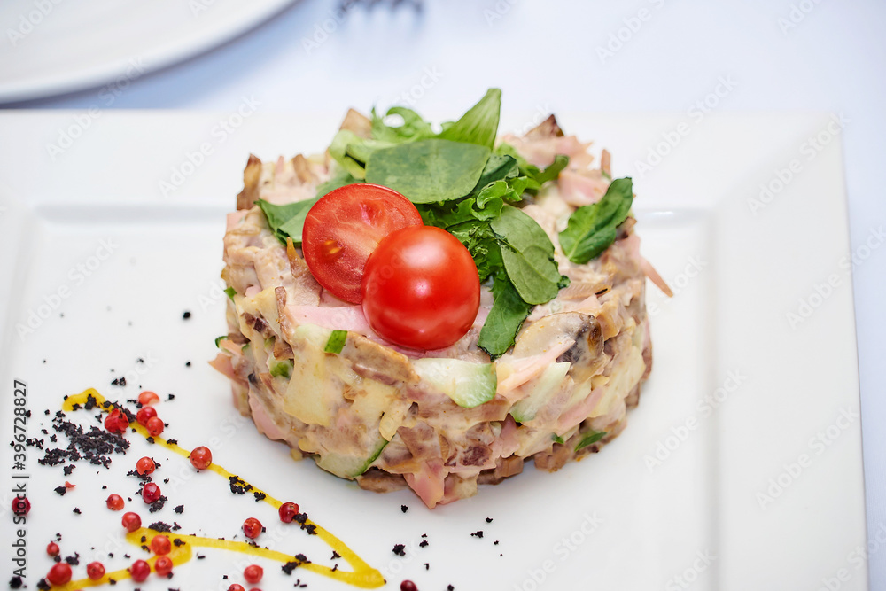 Russian meat salad mayonnaise for dinner. Mayonnaise russian meat salad on white plate background. Salad with bovine tongue meat, cucumbers, mushroom, mayonnaise top view, flat lay lunch in restaurant