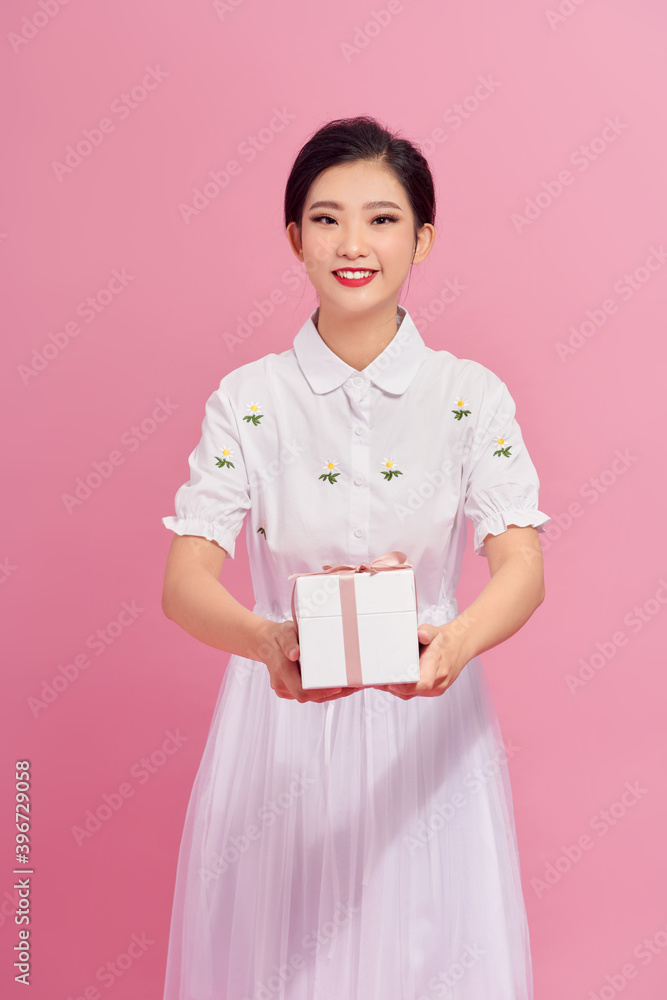 Portrait of a pretty smiling girl holding gift box and looking at camera isolated over pink background Portrait of a pretty smiling girl holding gift box and looking at camera isolated over pink background