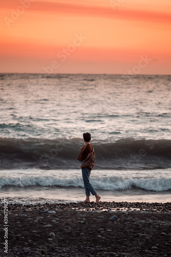 Fototapeta Naklejka Na Ścianę i Meble -  The girl looks at the ocean after sunset