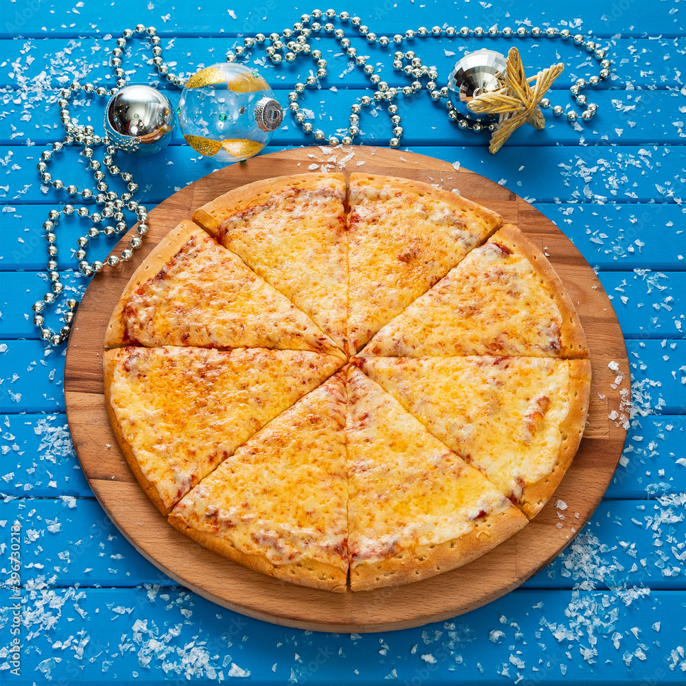 Pizza. Happy New Year and Christmas celebrations. Original design of the blue wooden table in the dining room with freshly prepared Pizza Margarita. Christmas eve