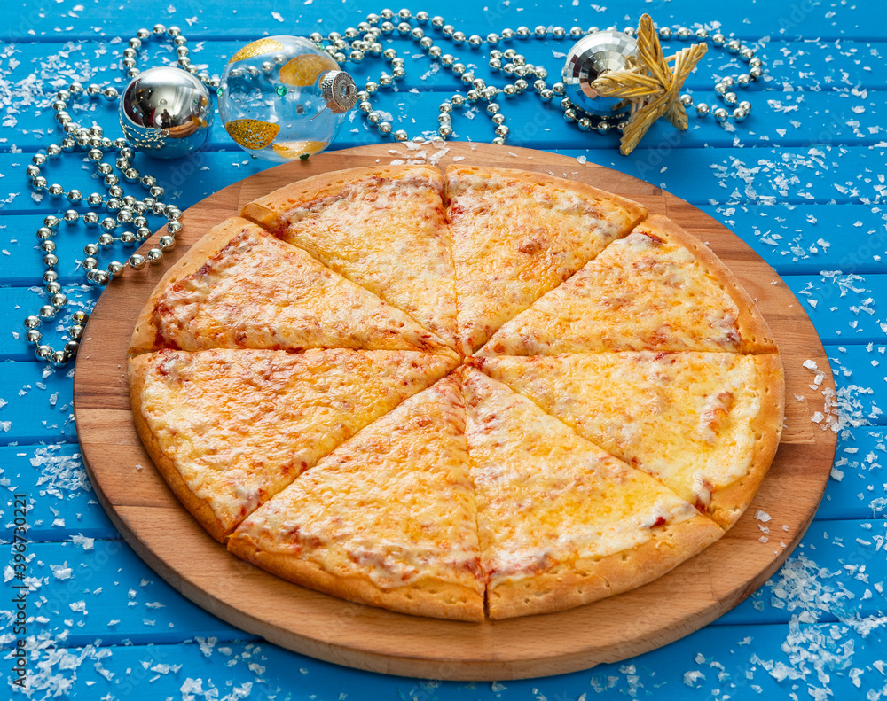 Pizza. Happy New Year and Christmas celebrations. Original design of the blue wooden table in the dining room with freshly prepared Pizza Margarita. Christmas eve