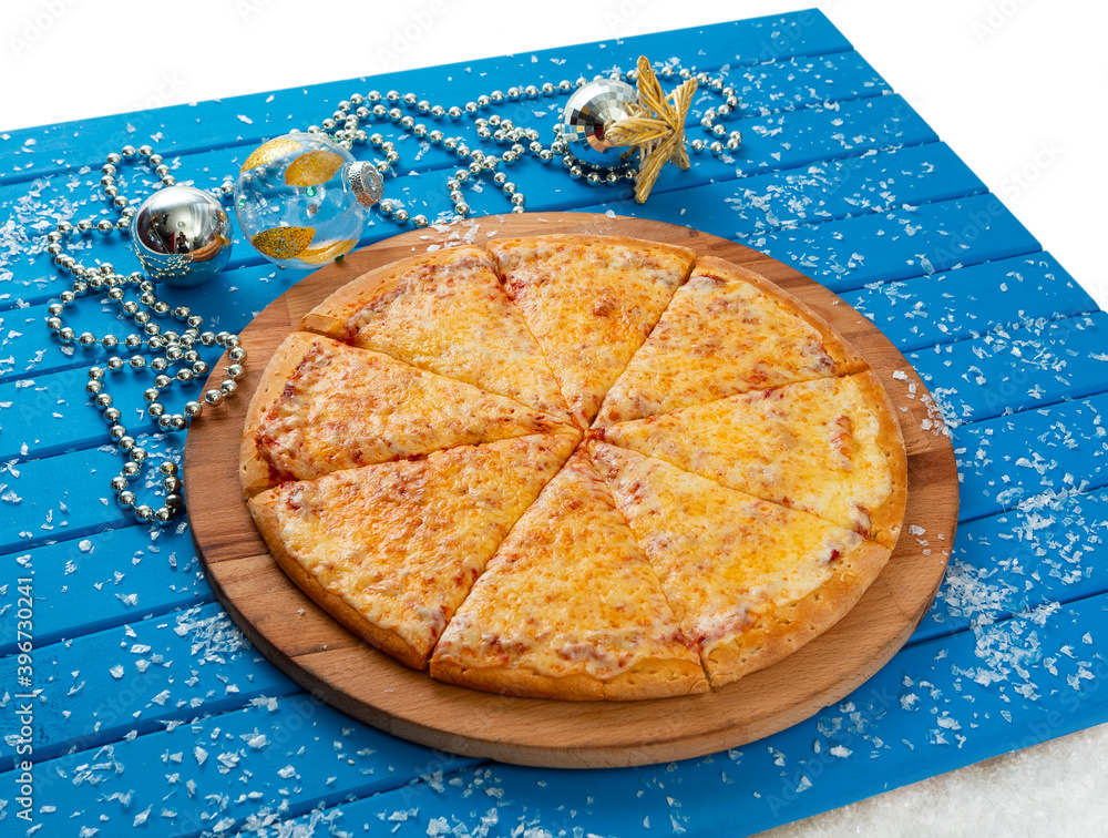 Pizza. Happy New Year and Christmas celebrations. Original design of the blue wooden table in the dining room with freshly prepared Pizza Margarita. Christmas eve
