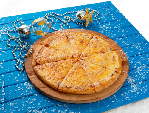 Pizza. Happy New Year and Christmas celebrations. Original design of the blue wooden table in the dining room with freshly prepared Pizza Margarita. Christmas eve