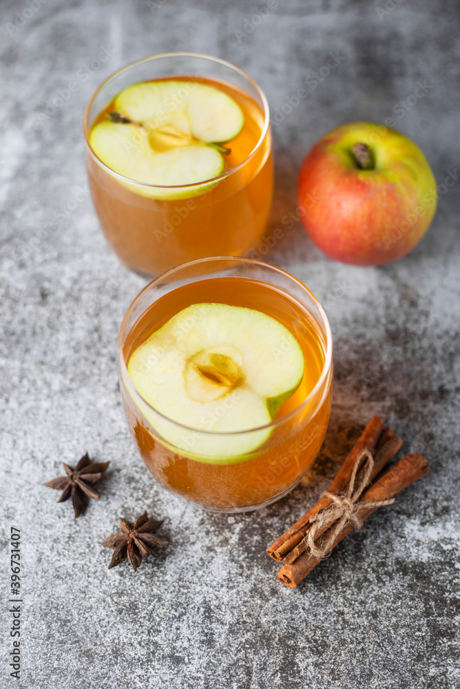Hot apple cider or punch on gray concrete background. Traditional Christmas or New Year warming spicy beverage with cinnamon, star anise. Non-alcoholic drink recipe idea for cold weather. Hot apple cider or punch on gray concrete background. Traditional Christmas or New Year warming spicy beverage with cinnamon, star anise. Non-alcoholic drink recipe idea for cold weather.