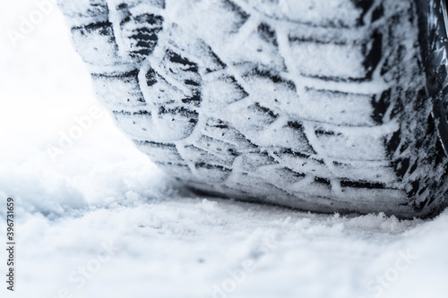Car tire in the snow close up. Car tracks on the snow. Traces of the car in the snow. Winter tires. Tyres covered with snow at winter road. Winter road safety concept © Aleksei