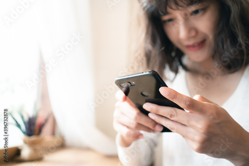 Close up hands of woman using smartphone chatting and searching information with blurry smiley face background. copy space of technology business and social distancing concept