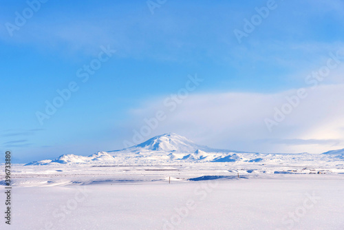 Typical Icelandic winter landscape with mountains under the snow and blue sky. Beautiful winter landscape with mountains covered snow, cold frosty weather and white field in Iceland.