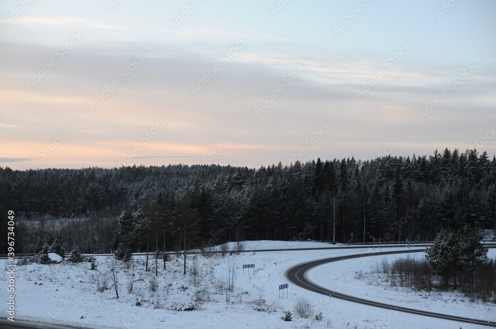 Winter driving on a snowy highway road during dusk and sunset in Sweden, Europe, Scandinavia Winter driving on a snowy highway road during dusk and sunset in Sweden, Europe, Scandinavia